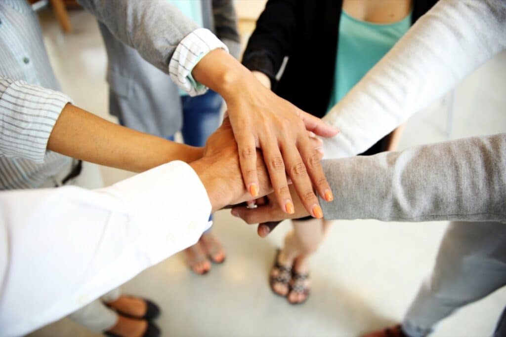 Team of high school entrepreneurs putting their hands together